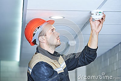 Worker installing smoke detector on the ceiling Stock Photo