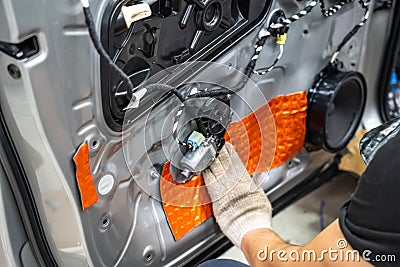 Worker installing special acoustic and vibration-damping material for noise insulation on car door. Soundproofing, auto Stock Photo