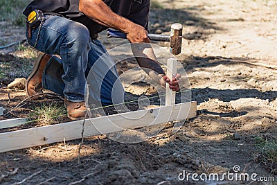 Worker Installing Stakes and Lumber Guides At Construction Site Stock Photo