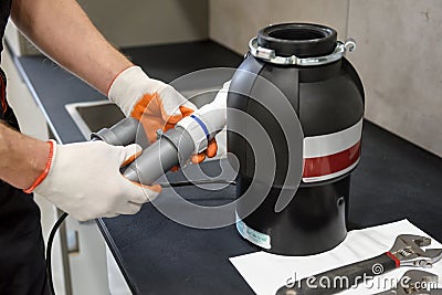 A worker is installing a waste shredder for the kitchen sink Stock Photo