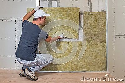 Worker insulating a room wall with mineral rock wool thermal insulation Stock Photo