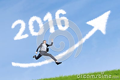 Worker jumps with numbers 2016 and upward arrow in sky Stock Photo