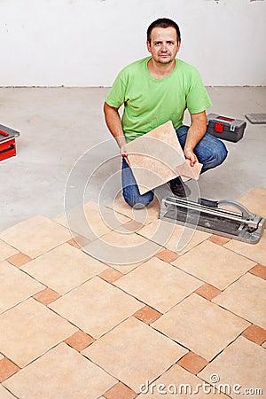 Worker laying floor tiles on concrete surface Stock Photo