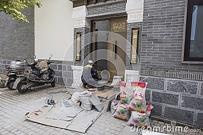 A worker laying floor tiles at the door Editorial Stock Photo