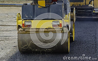 Worker leads the vibrating road roller to compact the asphalt laid out for the construction of a road Stock Photo