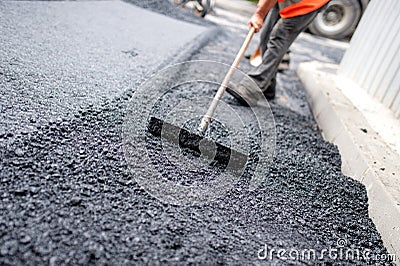 Worker leveling fresh asphalt on a road construction site Stock Photo