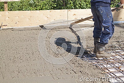 worker leveling fresh concrete slab with special working tool Stock Photo