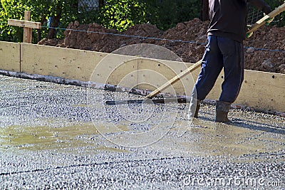 worker leveling fresh concrete slab with a special working tool Stock Photo