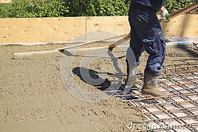 worker leveling fresh concrete slab with a special working tool Stock Photo