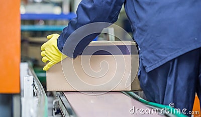 Production line with worker lifting box of conveyer belt. Stock Photo