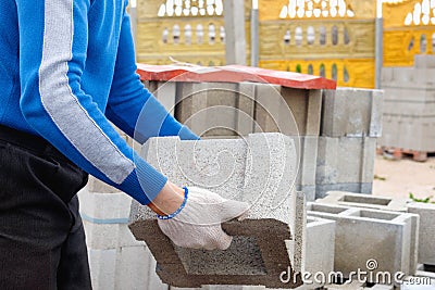 Worker loads cinder blocks from cement slurry for construction Stock Photo