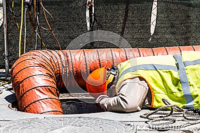 Worker Looking Down Manhole Editorial Stock Photo