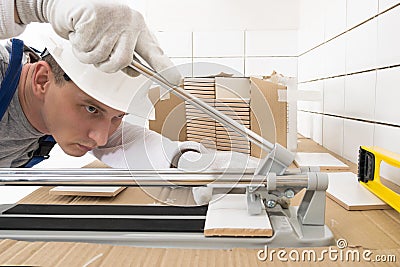 A worker makes a cut of a ceramic tile with a special tool, side view Stock Photo