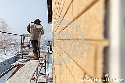 A worker makes mounting a wall on a house Stock Photo