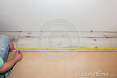 Worker making laminate flooring in apartment. Measure tape and pencil in hands. Maintenance repair renovation. Wooden parquet Stock Photo