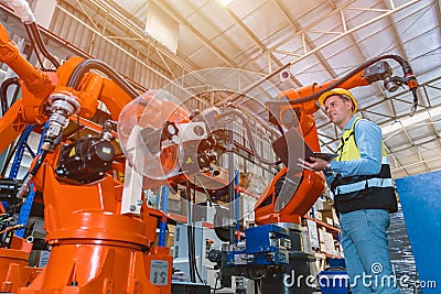 Worker man working with robot arm automate welding machine in modern metal factory. Engineer program robotic in heavy industry Stock Photo