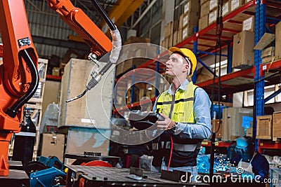 Worker man working with robot arm automate welding machine in modern metal factory. Engineer program robotic in heavy industry Stock Photo