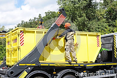 Worker managing crane of a truck and radioactive waste storage container loaded Editorial Stock Photo