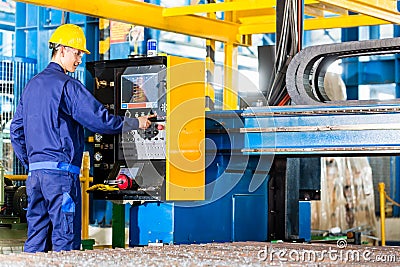 Worker in manufacturing plant at machine control panel Stock Photo