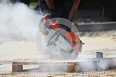 A worker mason cuts a curb with a circular saw when building a parking lot for tourist buses. Stock Photo