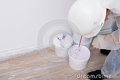 a worker mixes paint in a bucket with a mixer Stock Photo