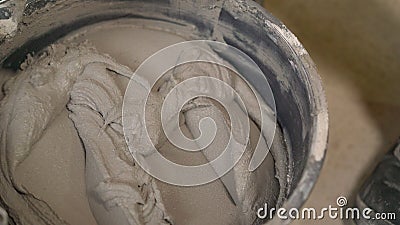 The worker mixes the solution in a bucket. A person mixes cement and water in a container to get the finished mixture. The Stock Photo