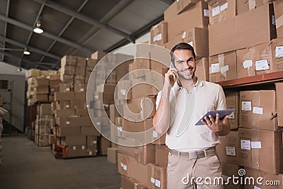 Worker with mobile phone and digital tablet in warehouse Stock Photo