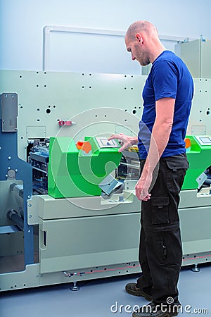 Worker next to the printing machine inputs the data by pressing the touch screen. Stock Photo