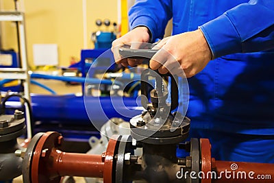 Worker opens valve on pipeline at industrial plant Stock Photo