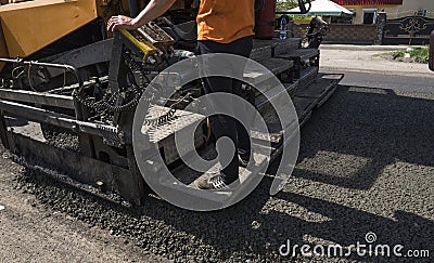 Worker operating asphalt paver machine during road construction and repairing works. A paver finisher, asphalt finisher Stock Photo