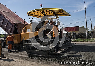 Worker operating asphalt paver machine during road construction and repairing works. A paver finisher, asphalt finisher Editorial Stock Photo