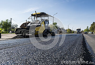 Worker operating asphalt paver machine during road construction and repairing works. A paver finisher, asphalt finisher Stock Photo