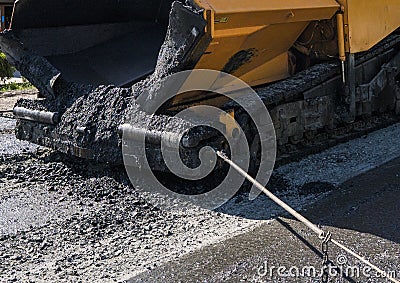 Worker operating asphalt paver machine during road construction and repairing works. A paver finisher, asphalt finisher Stock Photo