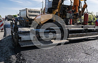 Worker operating asphalt paver machine during road construction and repairing works. A paver finisher, asphalt finisher Stock Photo