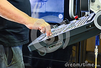 Worker, operator of the control panel of the program of operation of a high-precision CNC machining center, processing the manufac Stock Photo