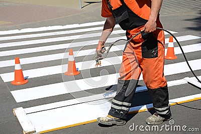 Worker is painting a pedestrian crosswalk. Technical road man worker painting and remarking pedestr Stock Photo