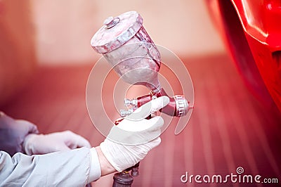 Worker painting a red car in painting booth using spray gun Stock Photo