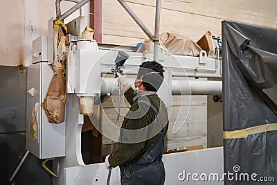 A worker painting to mechanical part with airless spray Stock Photo