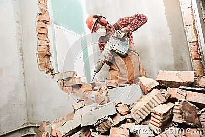 Worker with demolition hammer breaking interior wall Stock Photo