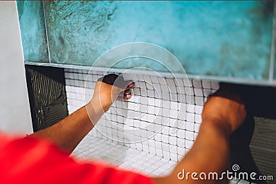 Worker placing ceramic mosaic boards on flexible adhesive. Worker hands working with ceramic tiles Stock Photo