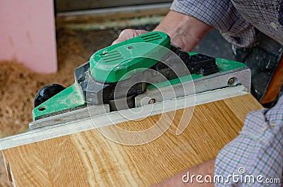 Worker planing the edge of massive oak stair with electrical plainer Stock Photo