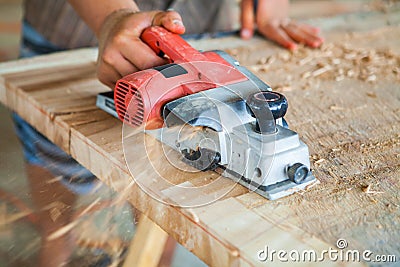 Worker planing a table top of wood with a electric plane Stock Photo