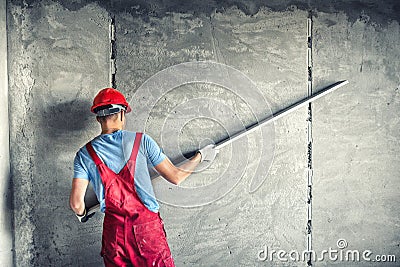 Worker with plastering tools renovating a house. builder worker plastering facade industrial building with leveler Stock Photo