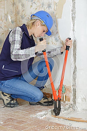 Worker plumber cutting sewerage pipe at construction site Stock Photo