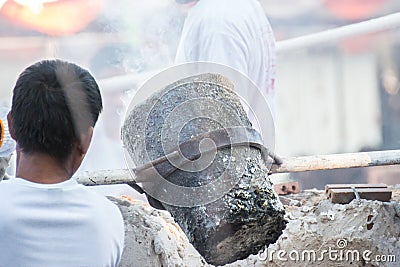 Worker pouring molten metal to casting Buddha statue Editorial Stock Photo