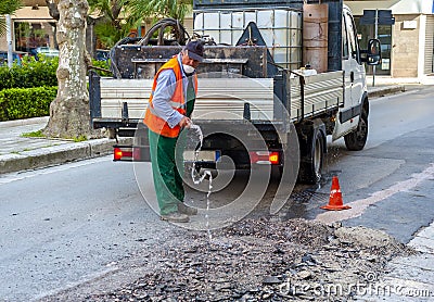 Worker pours water on the milled asphalt Stock Photo