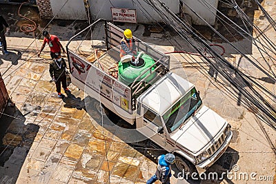 Worker prepares a chlorine-based disinfectant in a large tank while standing in the back of a pickup truck Editorial Stock Photo