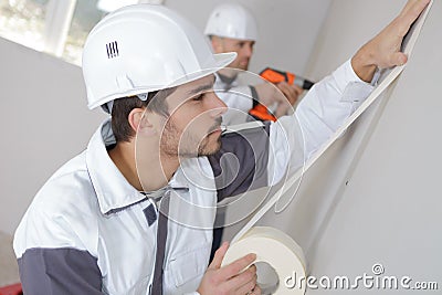 Worker protecting wall with masking tape before painting Stock Photo