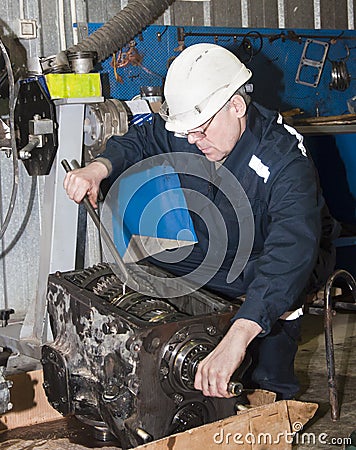 Worker in protective clothes repairs the automobile mechanism Stock Photo