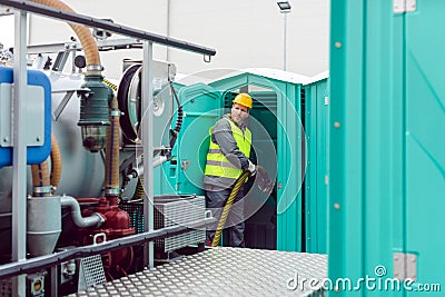 Worker pumping feces out of rental toilet for disposal Stock Photo